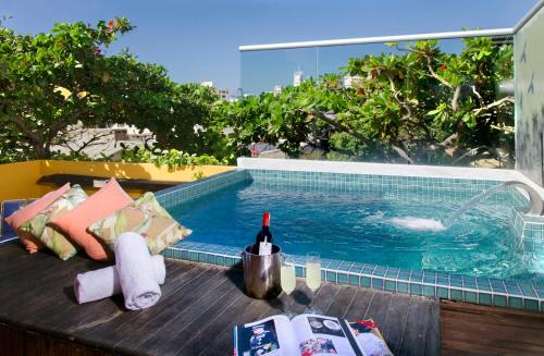a swimming pool with a bottle of wine on a table at Hotel Boutique Casa Mia in Santa Marta
