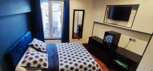 a bedroom with a bed and a tv and a mirror at Hôtel Moderne in Saint-Denis