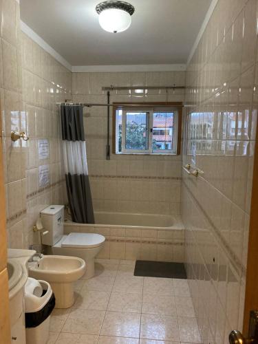 a bathroom with a tub and a toilet and a sink at Hospedaria Cidade Berço in Guimarães