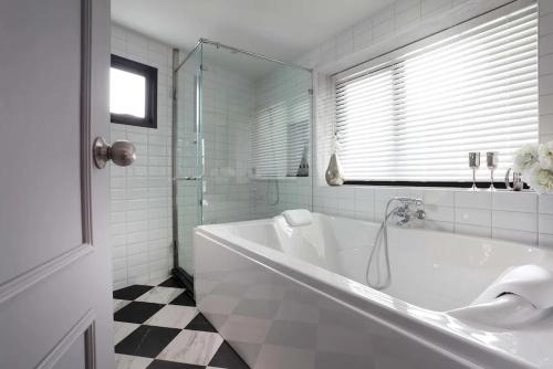 a white bathroom with a tub and a window at Hotel Dream - Luyen in Bangkok