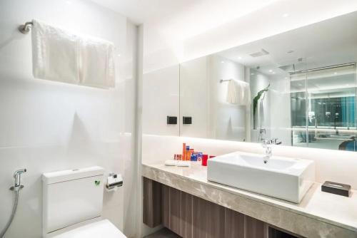 ein weißes Badezimmer mit einem Waschbecken und einem Spiegel in der Unterkunft Hotel Dream - Luyen in Bangkok