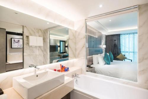 ein Bad mit einem Waschbecken, einem Spiegel und einem Bett in der Unterkunft Hotel Dream - Luyen in Bangkok