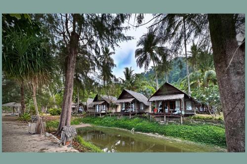 a group of cottages in a forest with trees at Coco Cottage - SHA Plus in Ko Ngai