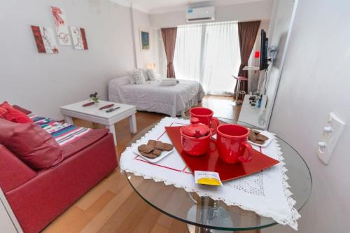 Departamento en Peña Recoleta MODERNO Y LUMINOSO في بوينس آيرس: غرفة معيشة مع طاولة وأريكة حمراء