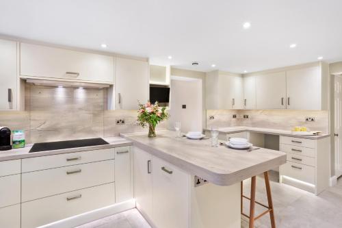 una cocina con armarios blancos y una mesa con flores. en Fountains Executive Apartment - Harrogate Stays, en Harrogate