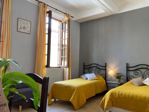 a bedroom with two beds and a window at La Vieille Demeure in Torreilles