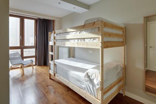 a bedroom with two bunk beds and a chair at Pamplonapartments Duque de Ahumada in Pamplona