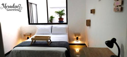 a bedroom with a bed with a table and a window at Moradia Laureles Medellin in Medellín