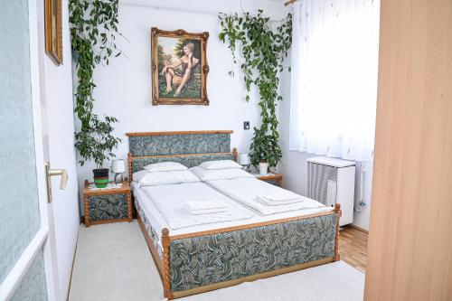 ハイドゥソボスローにあるLilla Vendégházのベッドルーム1室(ベッド1台付)が備わります。壁に絵が飾られています。