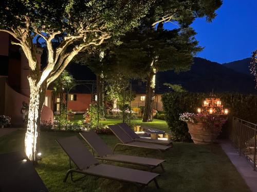 a yard with lounge chairs and a tree at night at Burlamacchi Villas in Bagni di Lucca