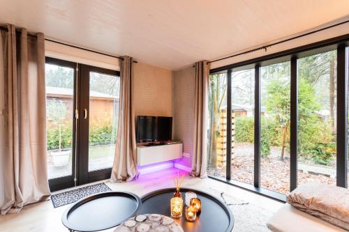 ein Wohnzimmer mit großen Fenstern und einem TV in der Unterkunft Boutique Chalet Veluwe in Putten