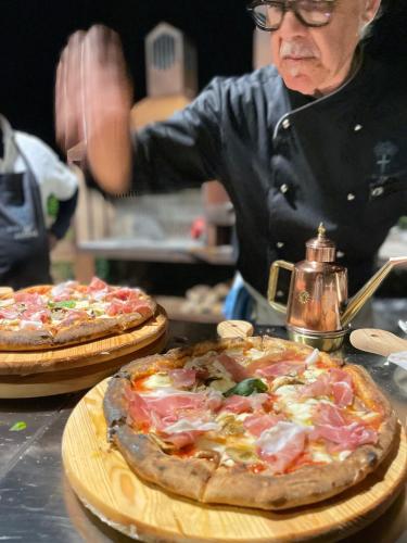 a woman standing in a kitchen with two pizzas at Burlamacchi Villas in Bagni di Lucca