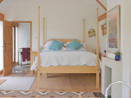 ein Schlafzimmer mit einem Himmelbett und blauen Kissen in der Unterkunft The Barn At Butts Farm in Wicken