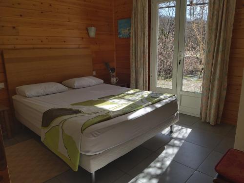 a bedroom with a bed in a room with a window at La Prairie in Noyers-sur-Jabron