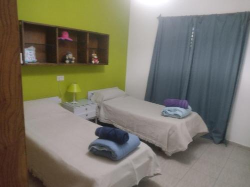 2 camas en una habitación con paredes verdes y cortinas azules en Rivadavia Mendoza -Casa López en Rivadavia