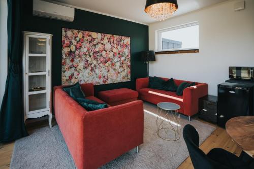 a living room with two red couches and a painting at Halacs Homes- Boutique cabins, Boutique Cabin in Balatonalmádi