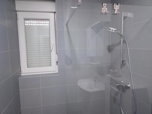 ein Bad mit einer Glasdusche, einem WC und einem Fenster in der Unterkunft Vila Cissa in Novalja
