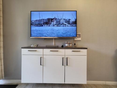 Elle comprend une télévision à écran plat installée au-dessus d'un meuble blanc. dans l'établissement Apartment 72 im Haus Villa Anna II, à Sankt Peter-Ording