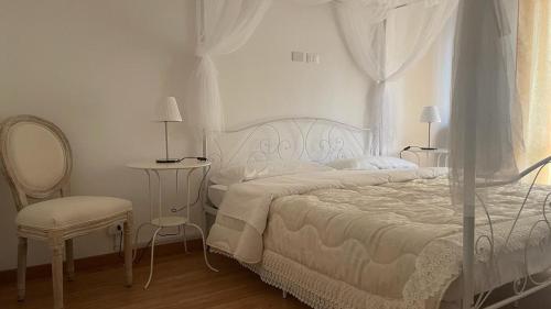 a white bedroom with a bed and a chair at Doctor House standard, suites & luxury rooms in Enna