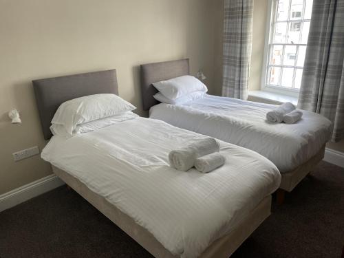two beds with towels on them in a bedroom at The Duke of Cornwall in St Austell