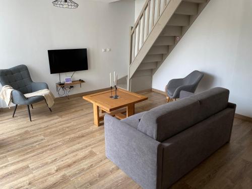 a living room with a couch and chairs and a tv at Chez Iréne in Villiers-aux-Chênes