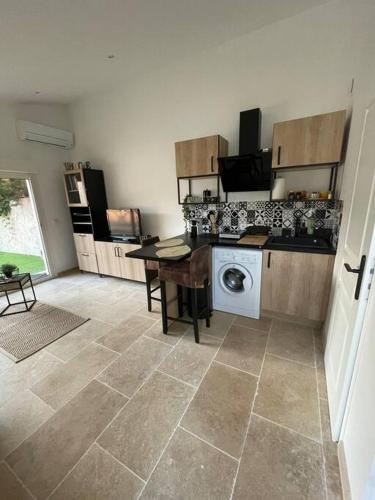 une cuisine avec une machine à laver et une table dans l'établissement Studio indépendant à mi-chemin entre aix et cassis, à Aubagne