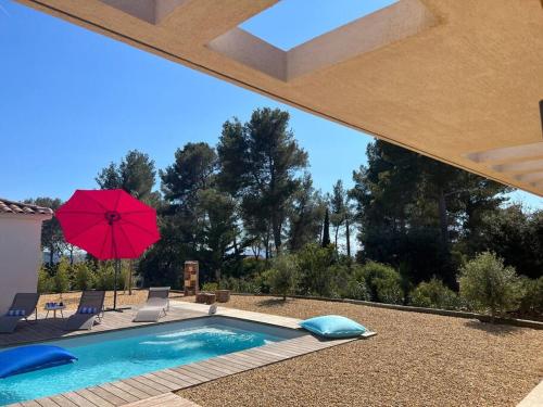 une piscine avec un parasol rouge et des chaises ainsi qu'une terrasse dans l'établissement La Villa Douce, entre terre et mer, à Laouque