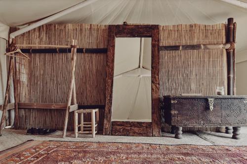 een kamer met een spiegel, een tafel en een kruk bij Heenat Salma Farm in Mu‘askar al Buşayyir