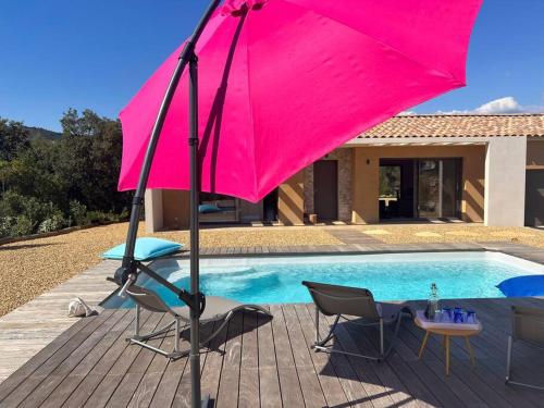 un parasol rose assis à côté d'une piscine dans l'établissement La Villa Douce, entre terre et mer, à Laouque