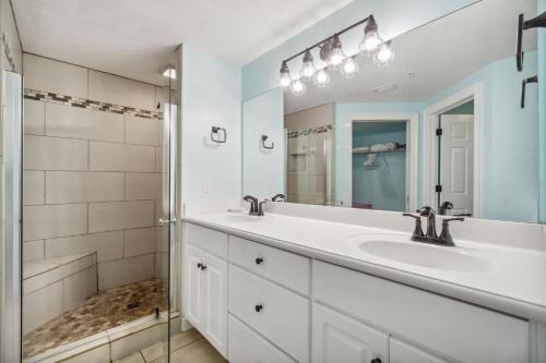 La salle de bains blanche est pourvue d'un lavabo et d'une douche. dans l'établissement Treasure Island 1005, à Panama City Beach