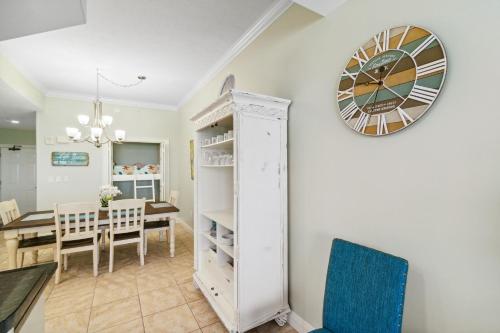 a dining room and living room with a clock on the wall at Treasure Island 0303 in Panama City Beach