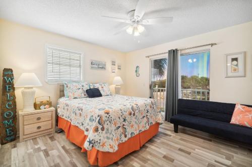 a bedroom with a bed and a couch and a window at Bellas Beach House in Panama City Beach