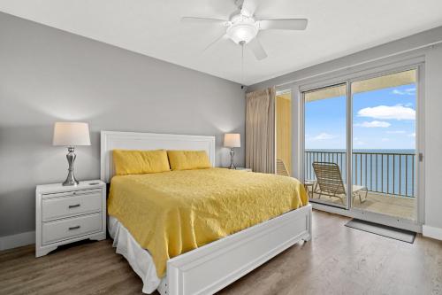 a bedroom with a bed with a yellow bedspread and a balcony at Treasure Island 2306 in Panama City Beach