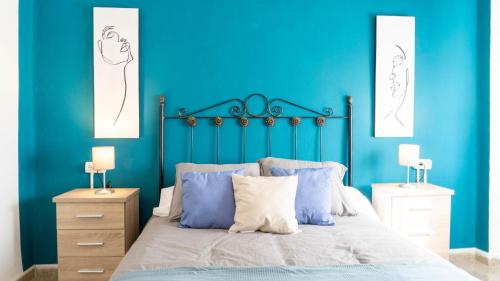 a bedroom with blue walls and a bed with blue pillows at Home Amatista Málaga in Málaga