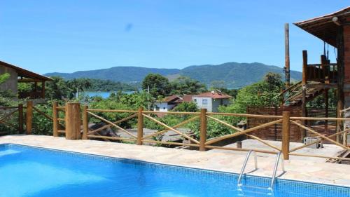 a swimming pool with a wooden fence around it at Chalés Yababali in Ubatuba