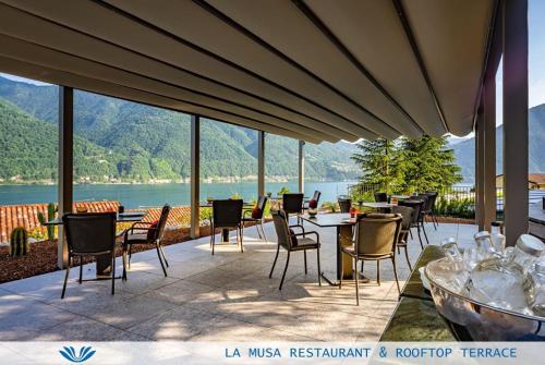 a patio with tables and chairs and a view of a lake at Parco San Marco Lifestyle Beach Resort in Porlezza
