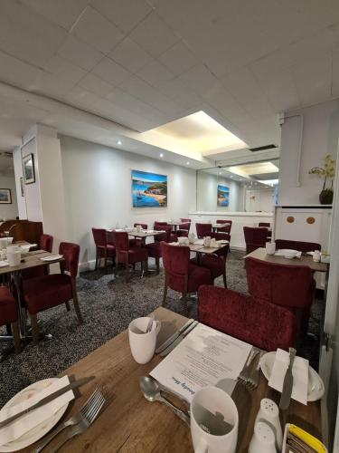 un comedor con mesas y sillas en un restaurante en Regina Hotel, en Torquay