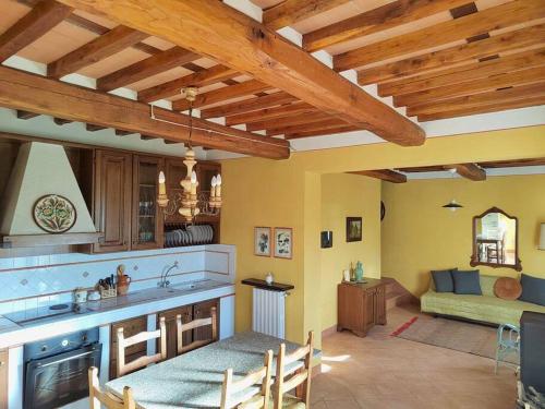a large kitchen with wooden ceilings and a living room at Villa Donnola: casa Rosmarino in Fucecchio