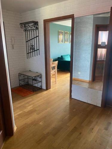a living room with wooden floors and a room with a table at Przestronny apartament in Giżycko