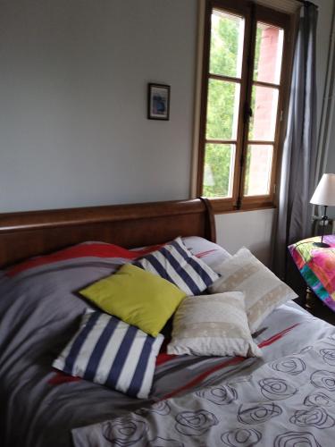 Bett mit Kissen und Fenster in der Unterkunft Helocar in Morlaix