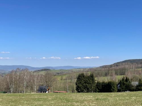 un campo de hierba con una casa en la distancia en Chata GOLDENBACH, en Malá Morava