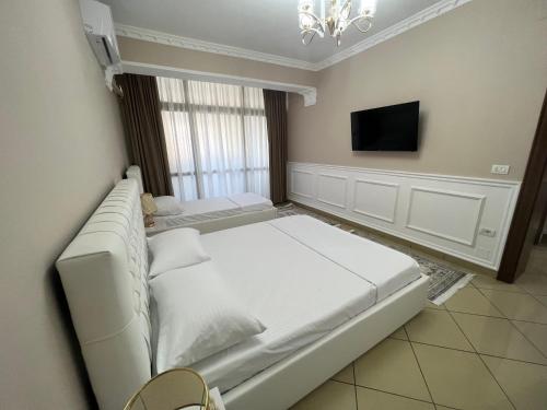 a bedroom with a large white bed and a tv at SaEl Apartments in Shkodër