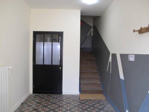 un couloir avec une porte noire et un escalier dans l'établissement POLIGNY : appartement refait à neuf !, à Poligny
