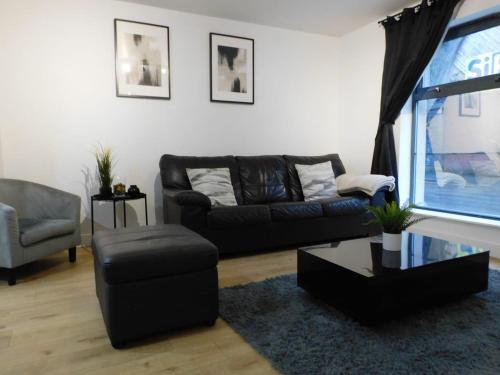 sala de estar con sofá negro y silla en 2 Bed Modern Apartment Manchester City Centre en Mánchester