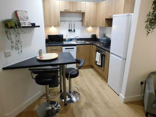 a kitchen with a black counter and a white refrigerator at 2 Bed Modern Apartment Manchester City Centre in Manchester