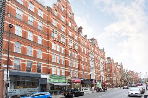 un gran edificio de ladrillo rojo en una calle de la ciudad con coches en Spacious Central London 2 Bedroom Mansion Block Apartment, en Londres
