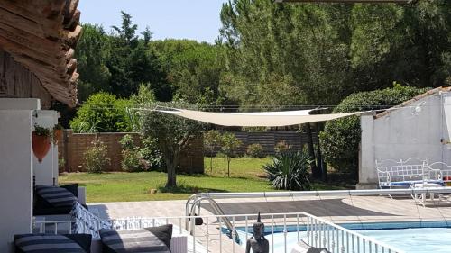 un patio avec un hamac au-dessus d'une piscine dans l'établissement Le Grau d'Agde: A vivre en famille et entre amis, au Grau-dʼAgde