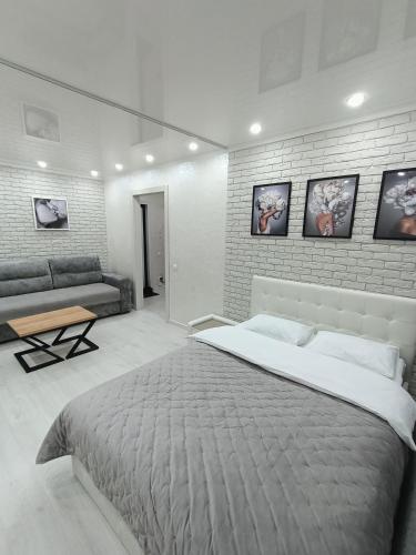 1 dormitorio con 1 cama grande y pared de ladrillo en Дизайнерская квартира в центре города, en Petropavlovsk