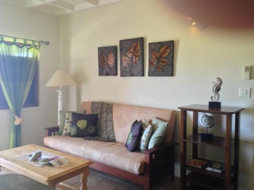 a living room with a couch and four paintings on the wall at Villa Touloulou in English Harbour Town