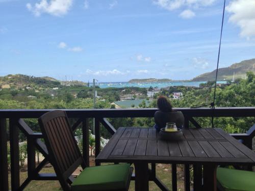 a woman sitting at a wooden table on a balcony at Villa Touloulou in English Harbour Town